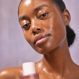 Woman holding Witches Brew toner with clear, glowing skin.