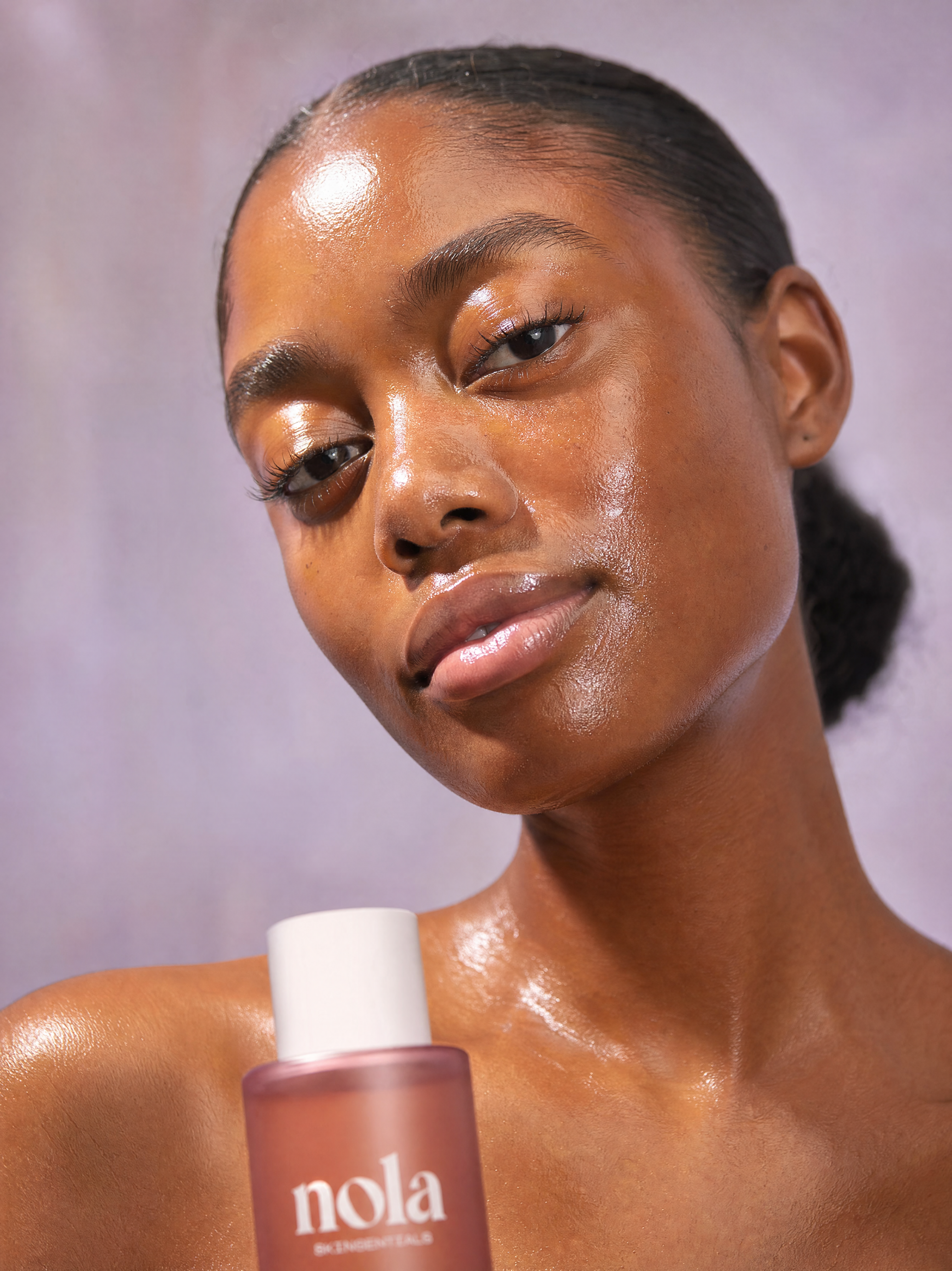 Woman holding Witches Brew toner with clear, glowing skin.