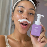 Woman smiling with a playful foam mustache from Clarifying Cleansing Foam.
