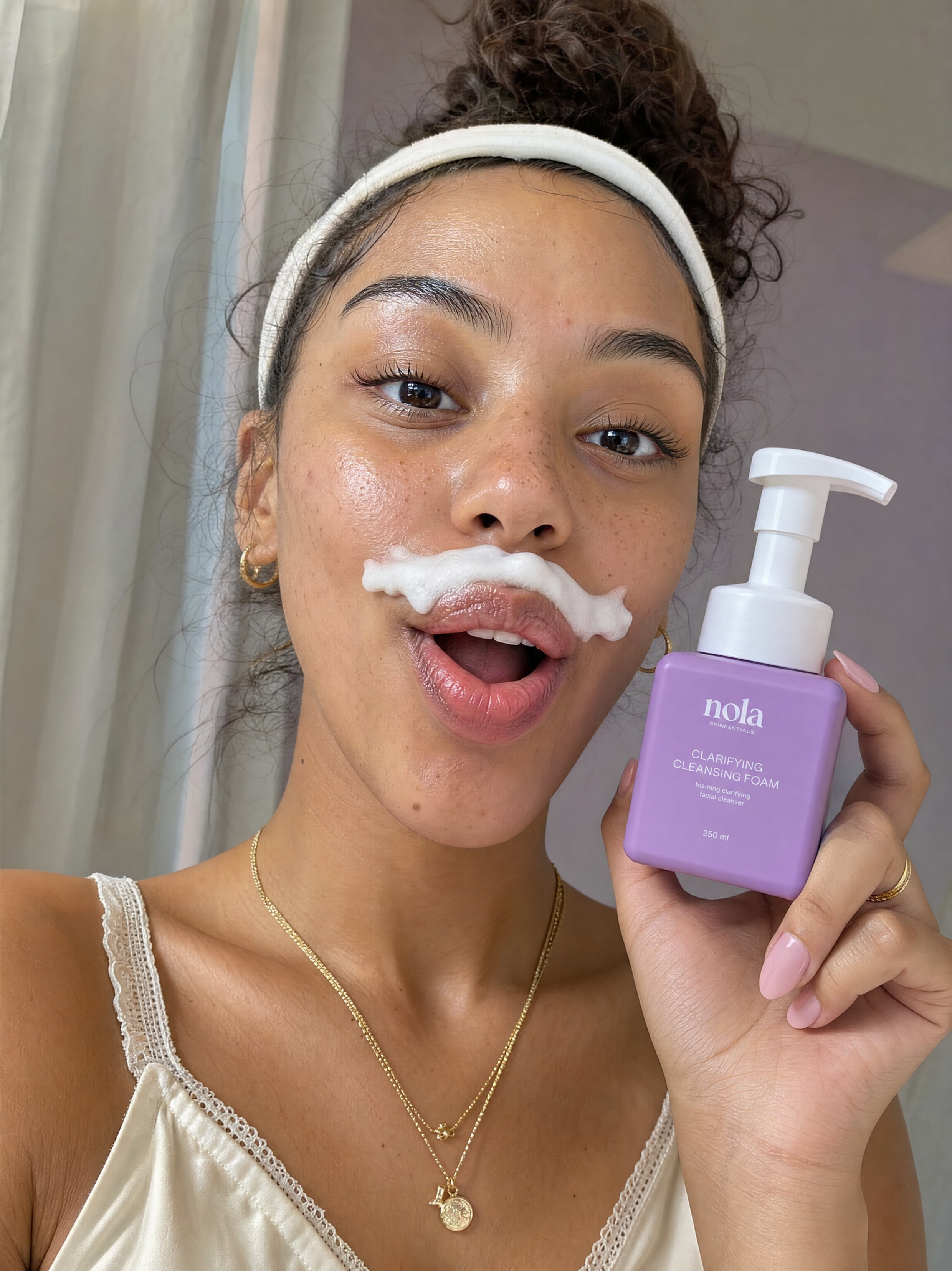 Woman smiling with a playful foam mustache from Clarifying Cleansing Foam.