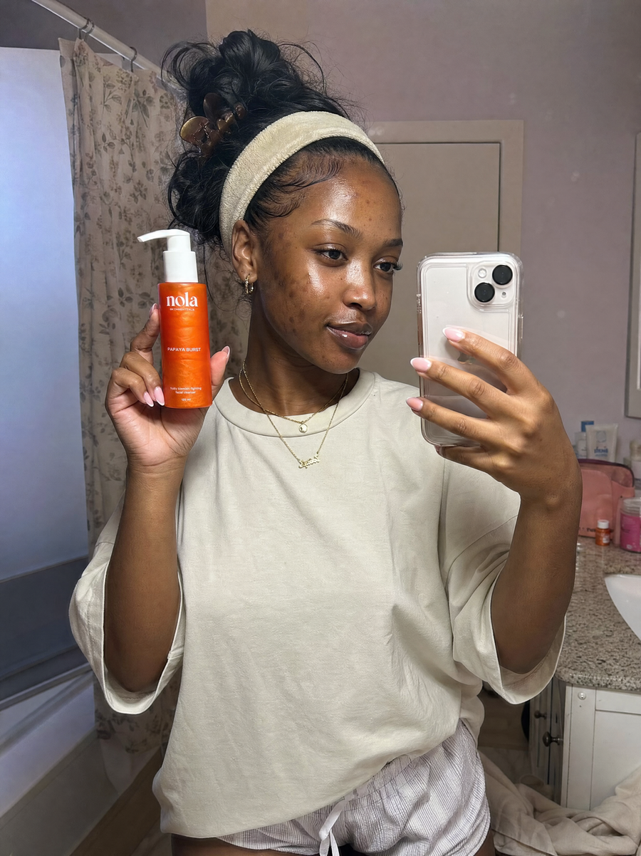 Woman holding the Papaya Burst facial cleanser bottle.
