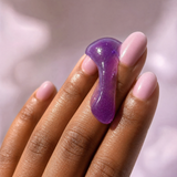 Close-up of purple jelly cleanser texture on fingertips.