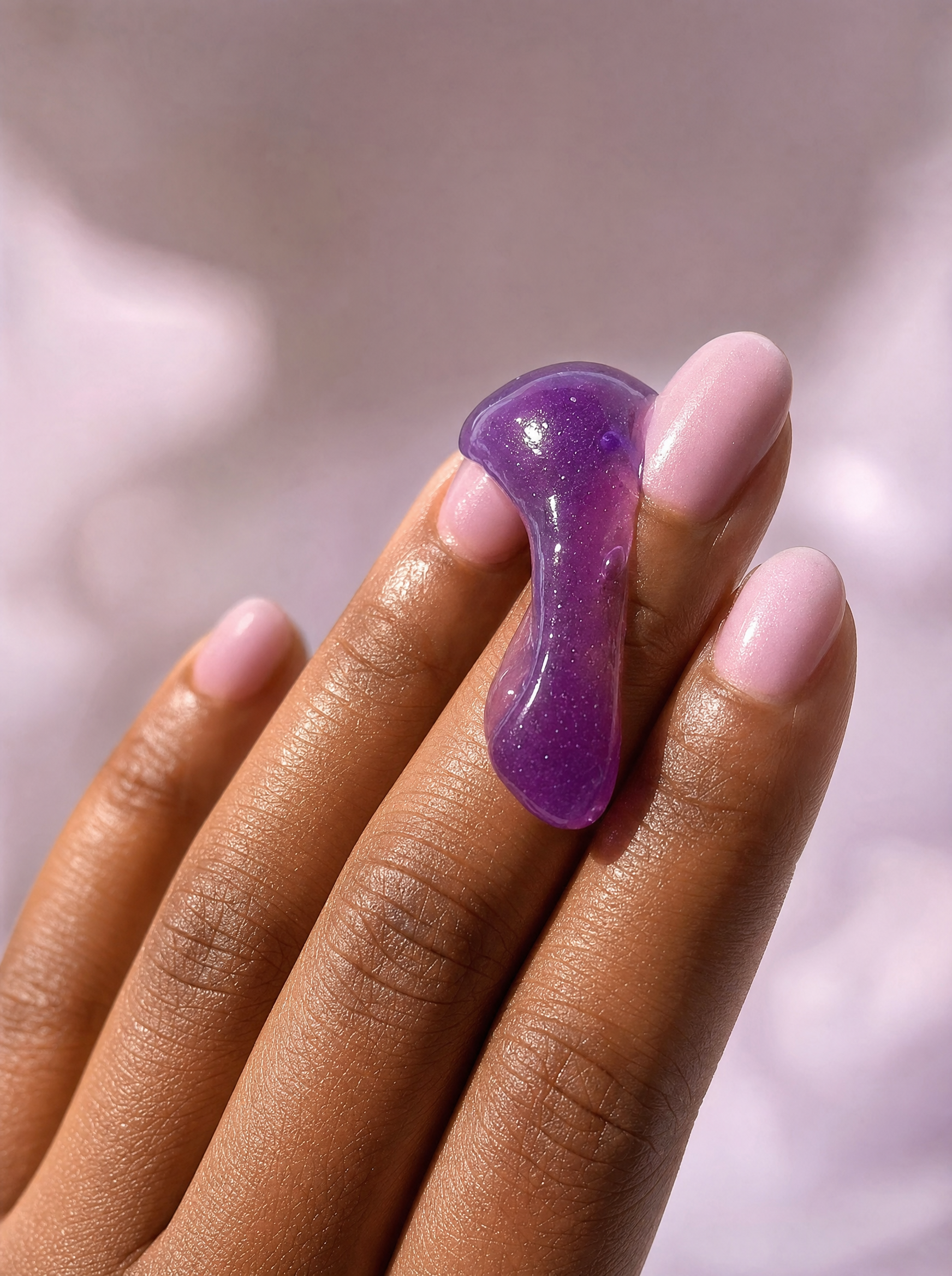 Close-up of purple jelly cleanser texture on fingertips.
