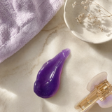 Flat lay of purple jelly cleanser with skincare accessories.