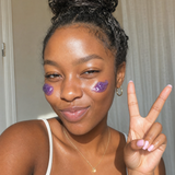 Woman smiling with purple jelly cleanser dotted on her cheeks.
