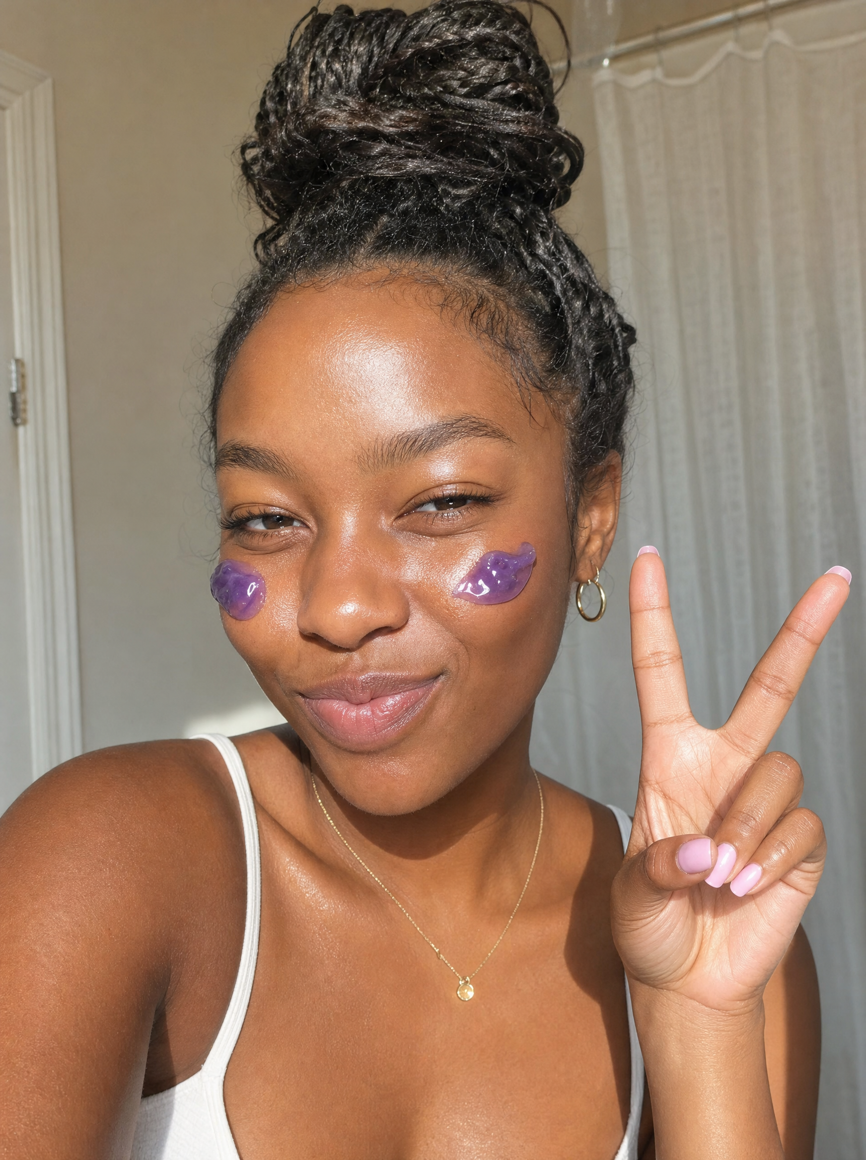 Woman smiling with purple jelly cleanser dotted on her cheeks.