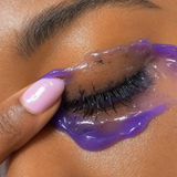 Purple jelly cleanser dissolving eye makeup while cleansing the face.
