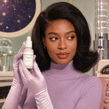 Model holding Hydra Hottie Serum in a soft lavender beauty campaign by NOLA Skinsentials