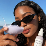 Model holding Hydra Hottie Serum outdoors in lavender-toned lifestyle shot by NOLA Skinsentials