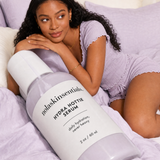 Model in lavender pajamas relaxing with Hydra Hottie Serum bottle by NOLA Skinsentials