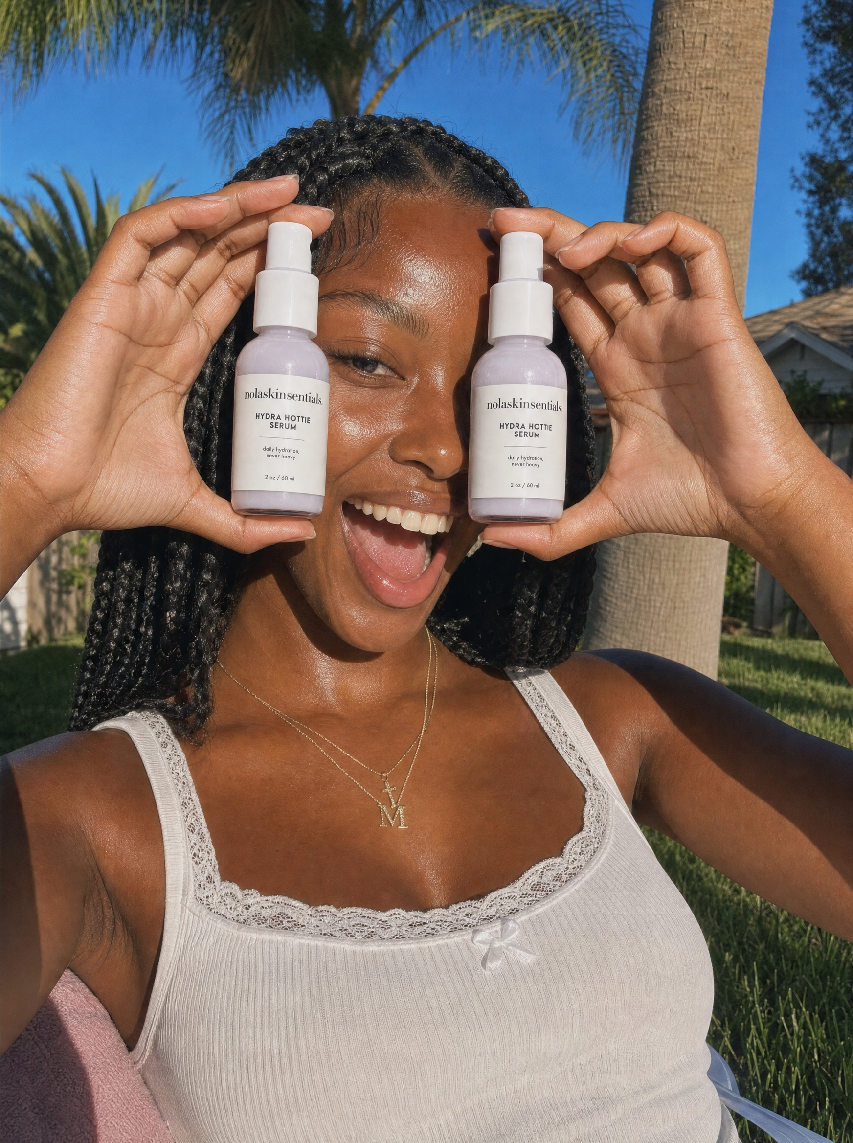 Smiling customer holding two Hydra Hottie Serum bottles outdoors — NOLA Skinsentials